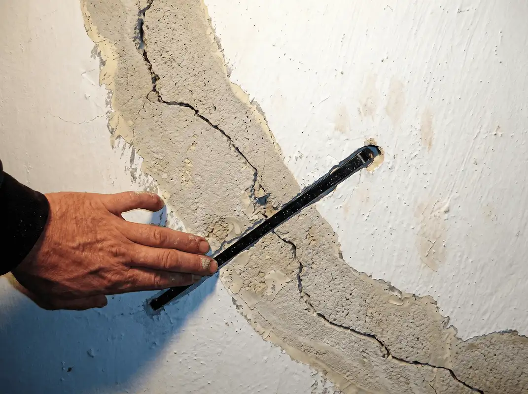 A wall with a large crack is being inspected by a professional in Marietta, GA